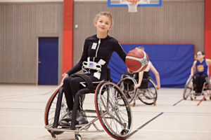 Bild på ung tjej som spelar rullstolsbasket och använder Mollii