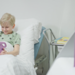 ett barn som ligger i en sjukhussäng och använder hublet